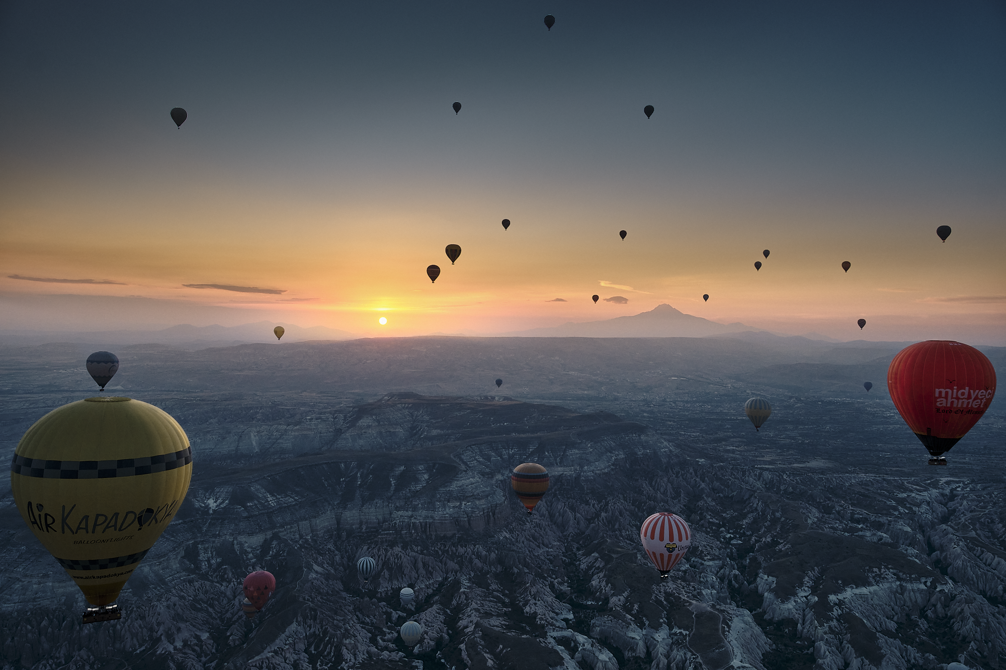Hot air balloons floating above Cappadocia during a quiet sunrise
