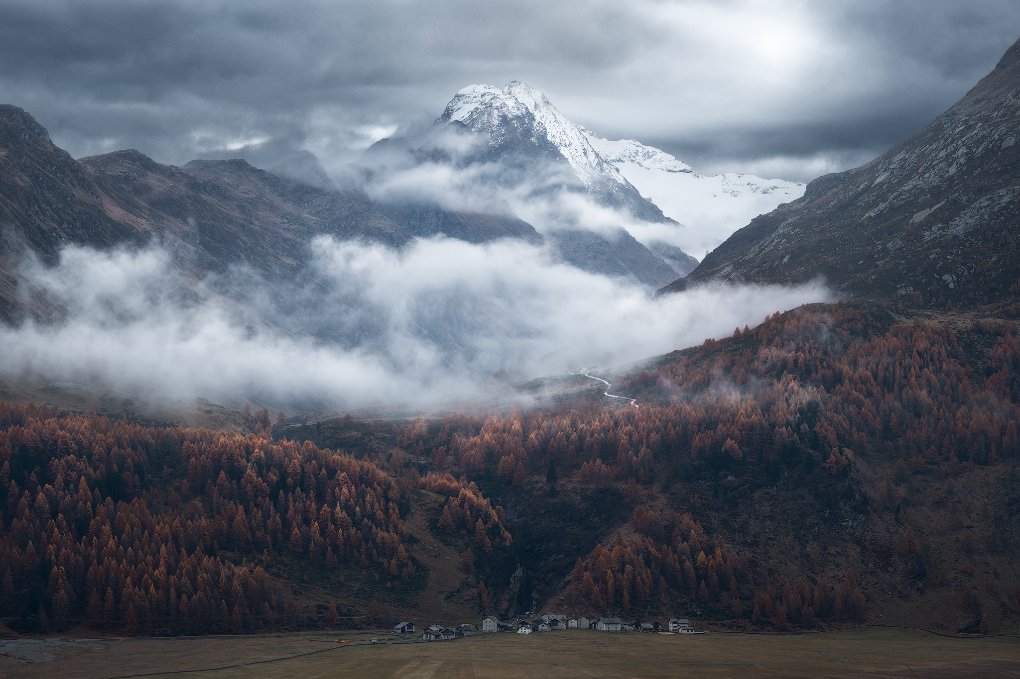 Snow-covered mountain rising above mist and an autumn forest in Switzerland
