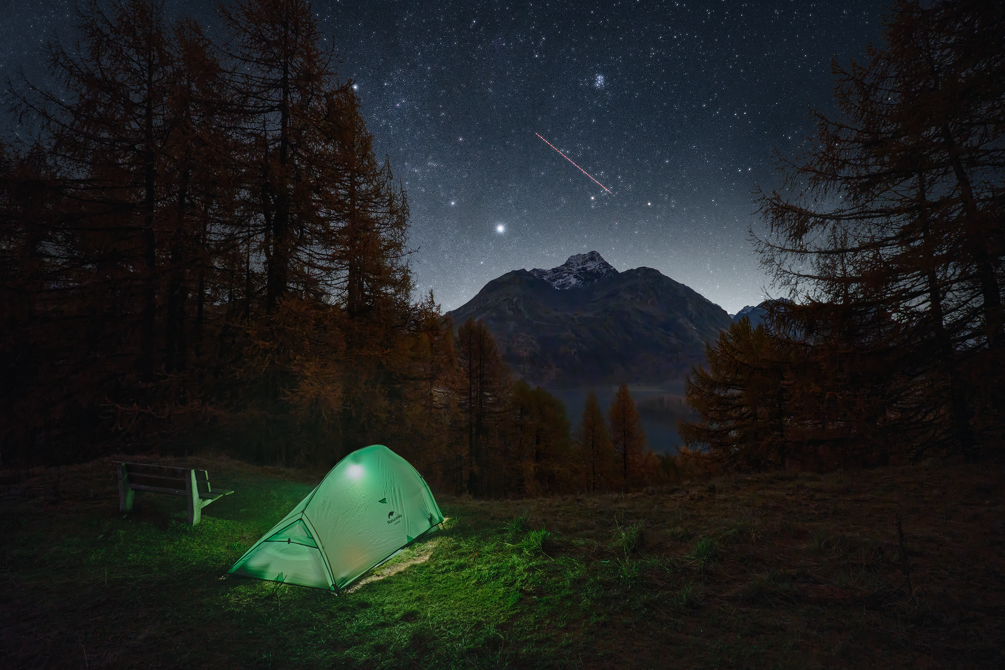 Illuminated green tent beneath a starry sky in the Swiss mountains