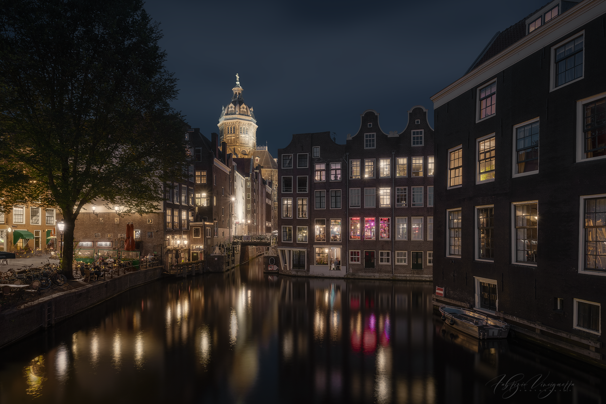 Historic canal houses and colourful reflections along an Amsterdam canal at night
